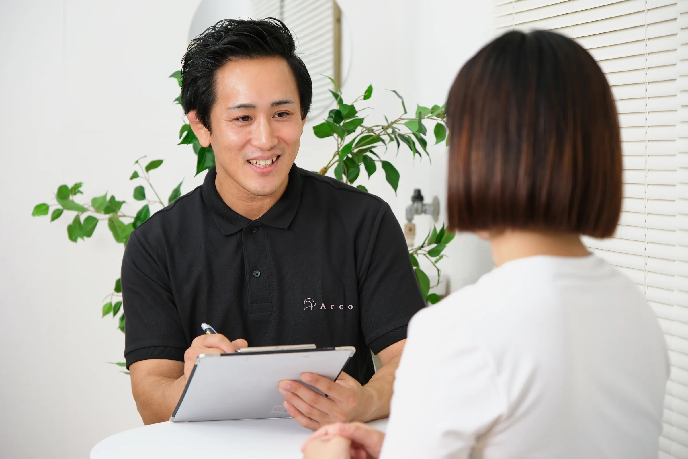 タブレットを手に、トレーナーが今後の通い方をご案内している様子